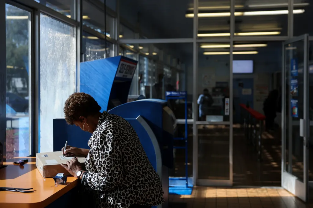 A customer writes an address on a box before shipping at the United States Postal Service Gardena Post Office.
