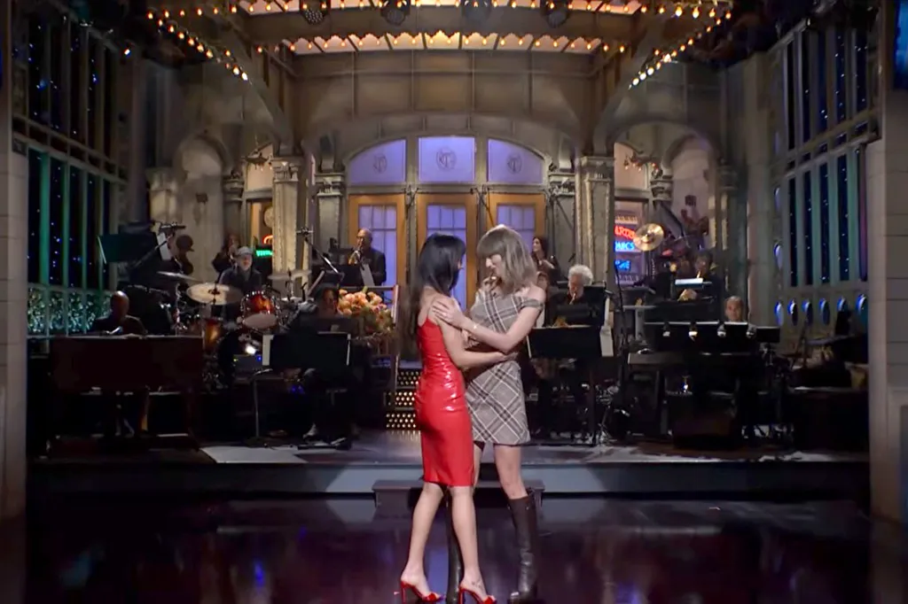 Dakota Johnson, in a red dress, is joined by Taylor Swift on stage during her opening monologue on Saturday Night Live.