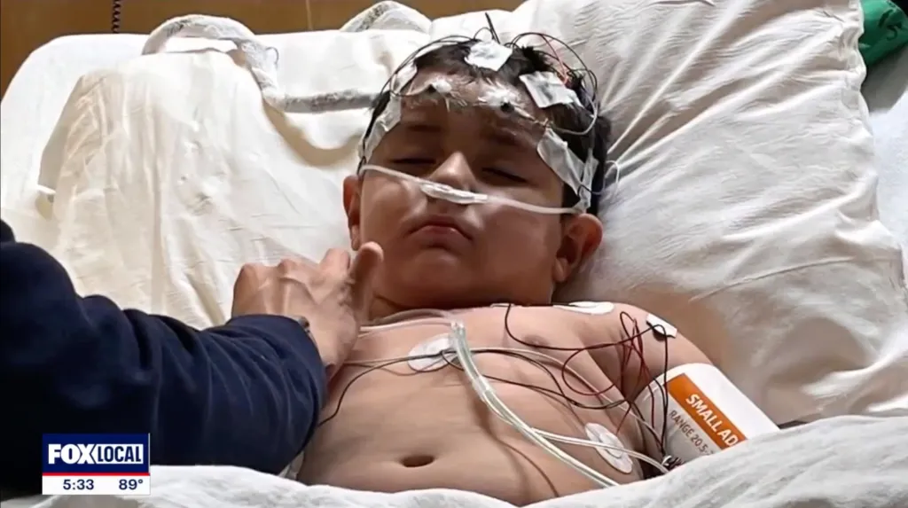 Kayla Price's 3-year-old terminally ill son, Devin, in a hospital bed with medical equipment attached to his head and body.