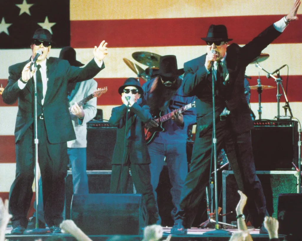 Dan Aykroyd, J. Evan Bonifant, and John Goodman perform on stage in the movie Blues Brothers 2000.