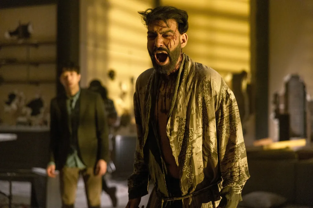 Rahul Kohli as Napoleon Usher in The Fall of the House of Usher, screaming in pain, with another man looking on in the background.
