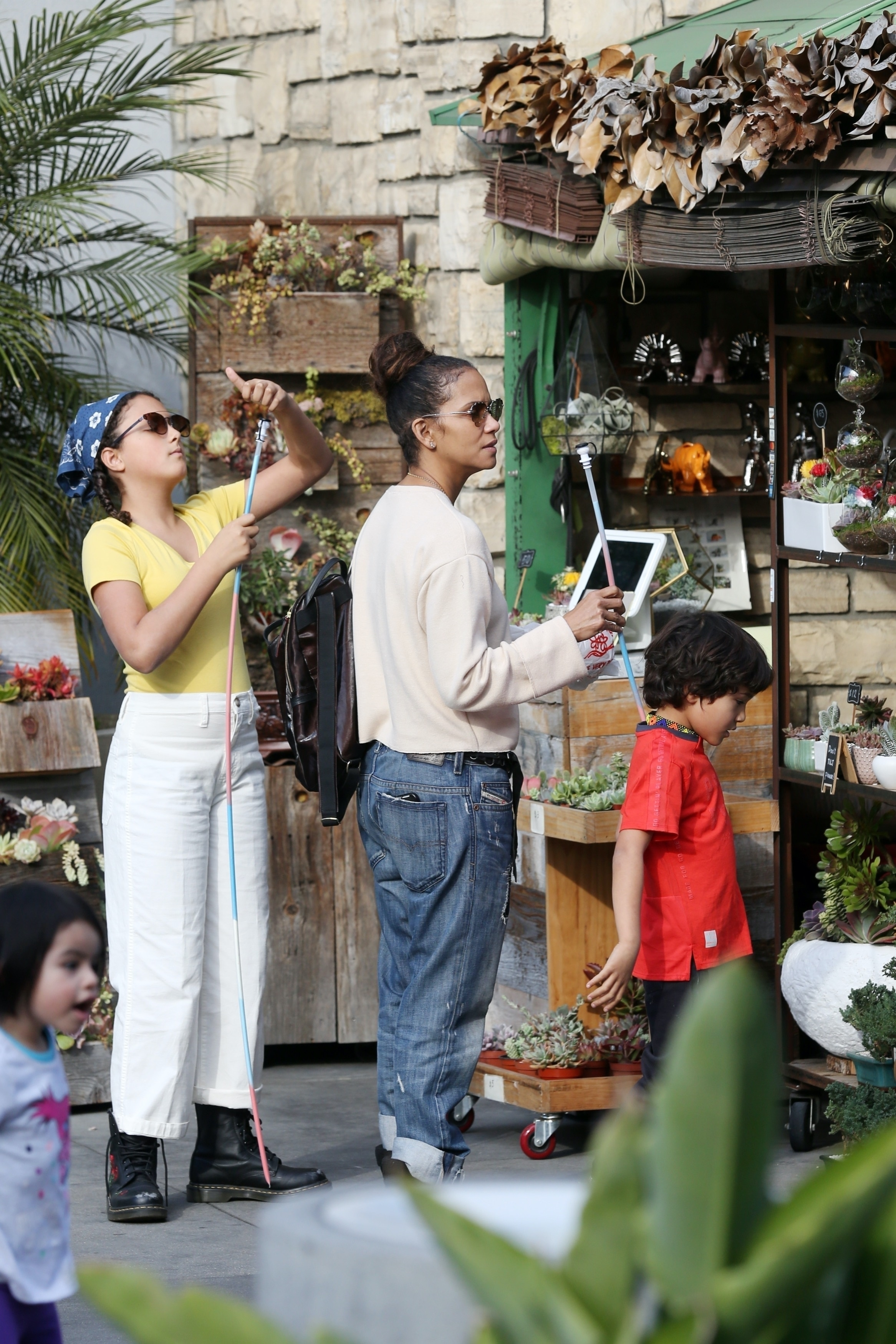 Halle Berry stands with her children, Nahla Ariela Aubry and Maceo Robert Martinez, near a shop displaying plants.