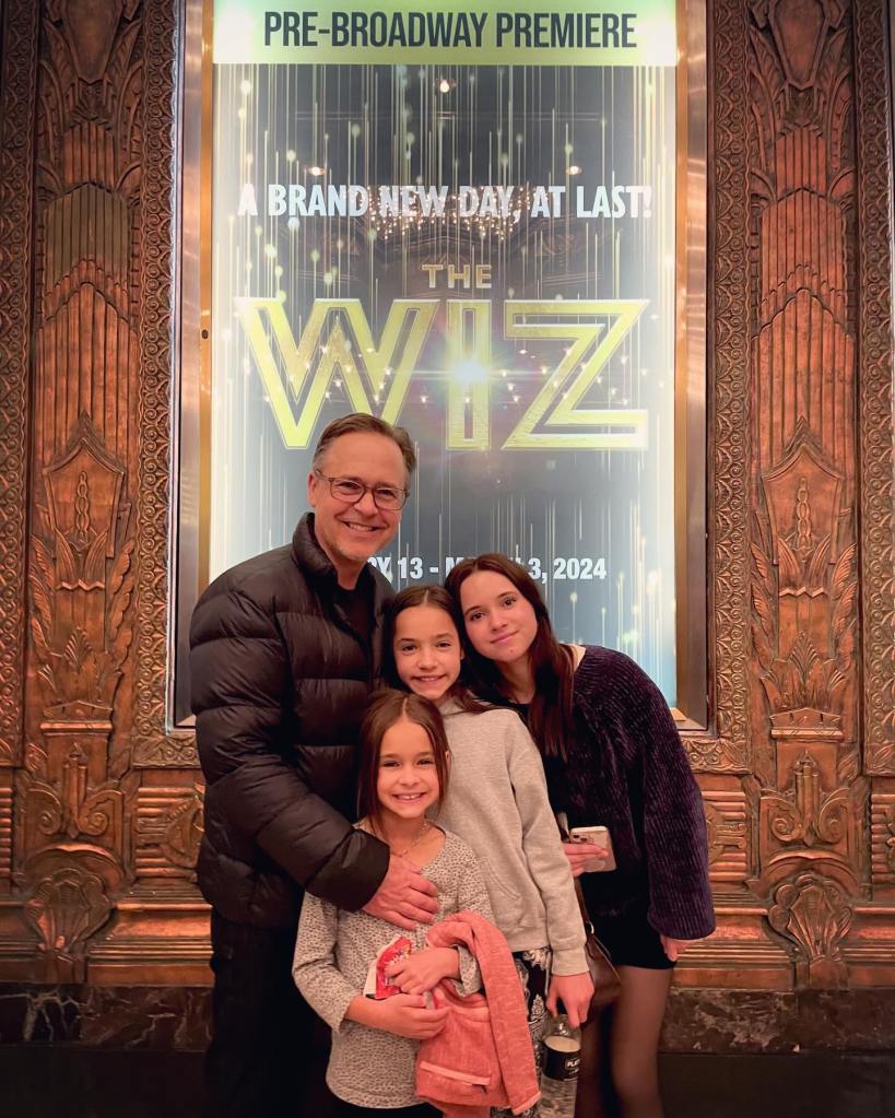 Chad Lowe and his daughters Mabel, Fiona, and Nixie pose in front of a poster for 