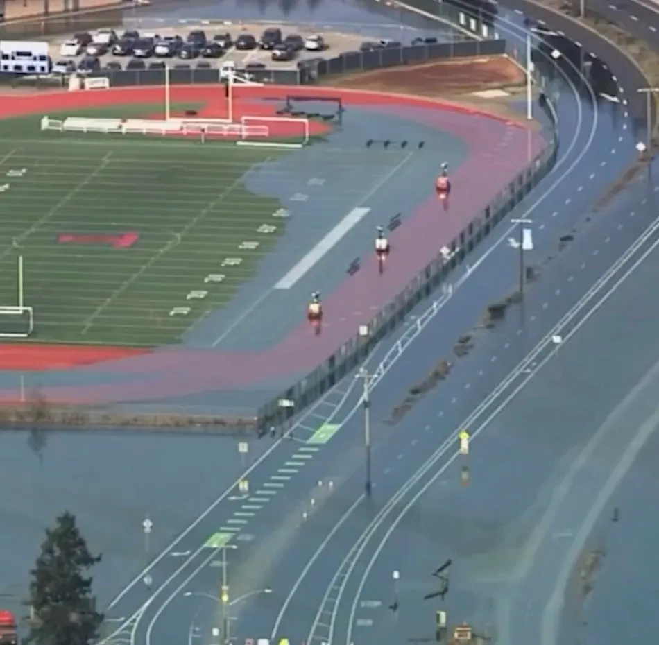 Aerial view of a flooded athletic field and surrounding roads.