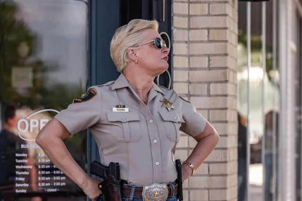 Sheriff Vela Thorne (Martha Plimpton) standing outside a building with her hands on her hips in 