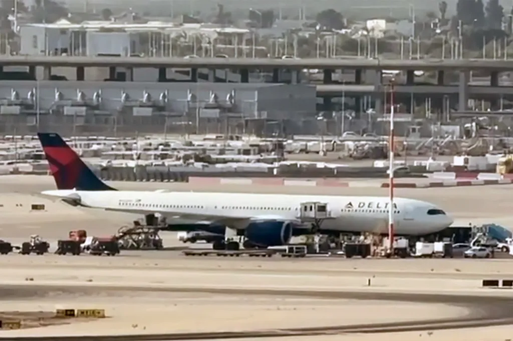 A Delta Air Lines passenger plane parked at an airport tarmac, surrounded by service vehicles.