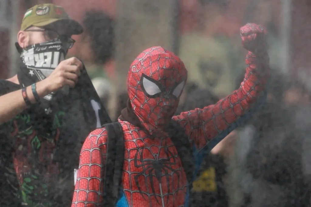 A demonstrator wearing a Spider-Man costume raises a fist during a protest in Liege.