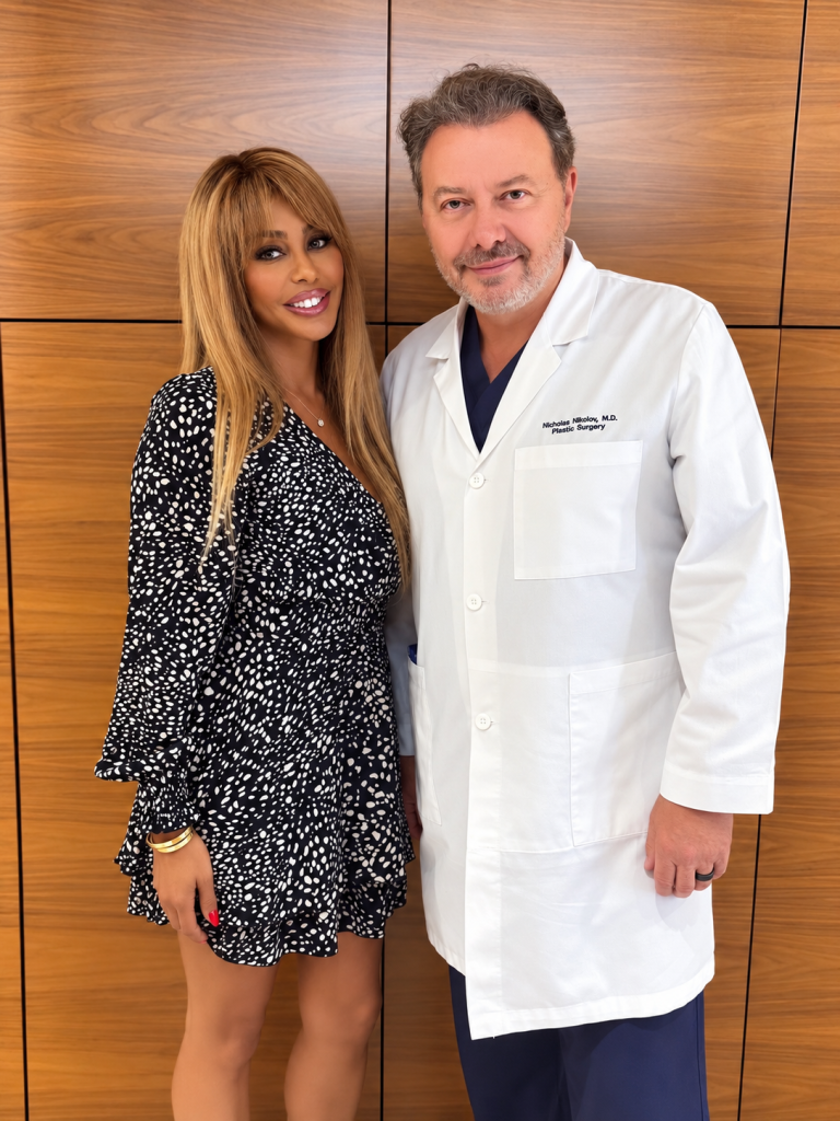 Singer Shyra Sanchez poses alongside Dr. Nicholes Nikolov in a doctor's office.