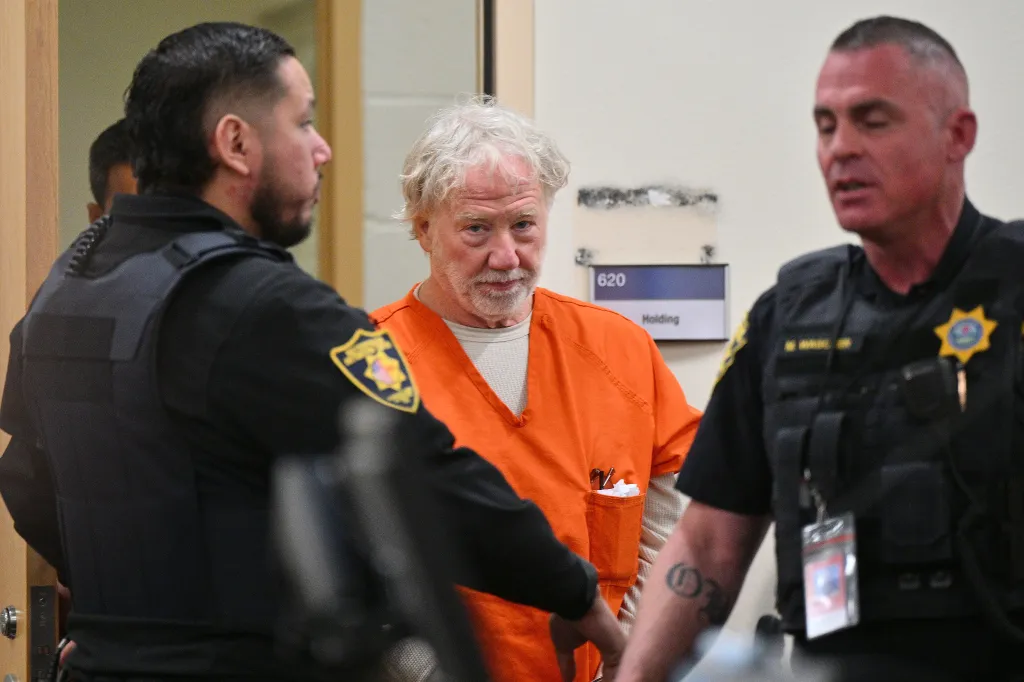 Director and actor Timothy Busfield arrives for a hearing at the Bernalillo County Courthouse flanked by two officers.