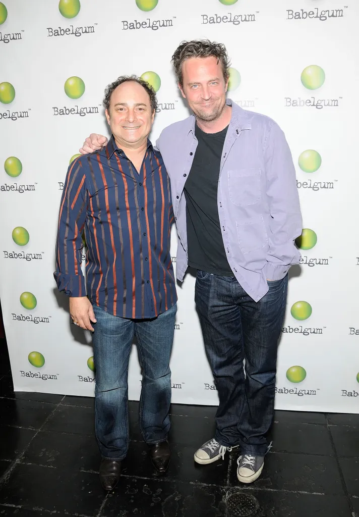 Director Kevin Pollak and actor Matthew Perry standing together in front of a branded backdrop.
