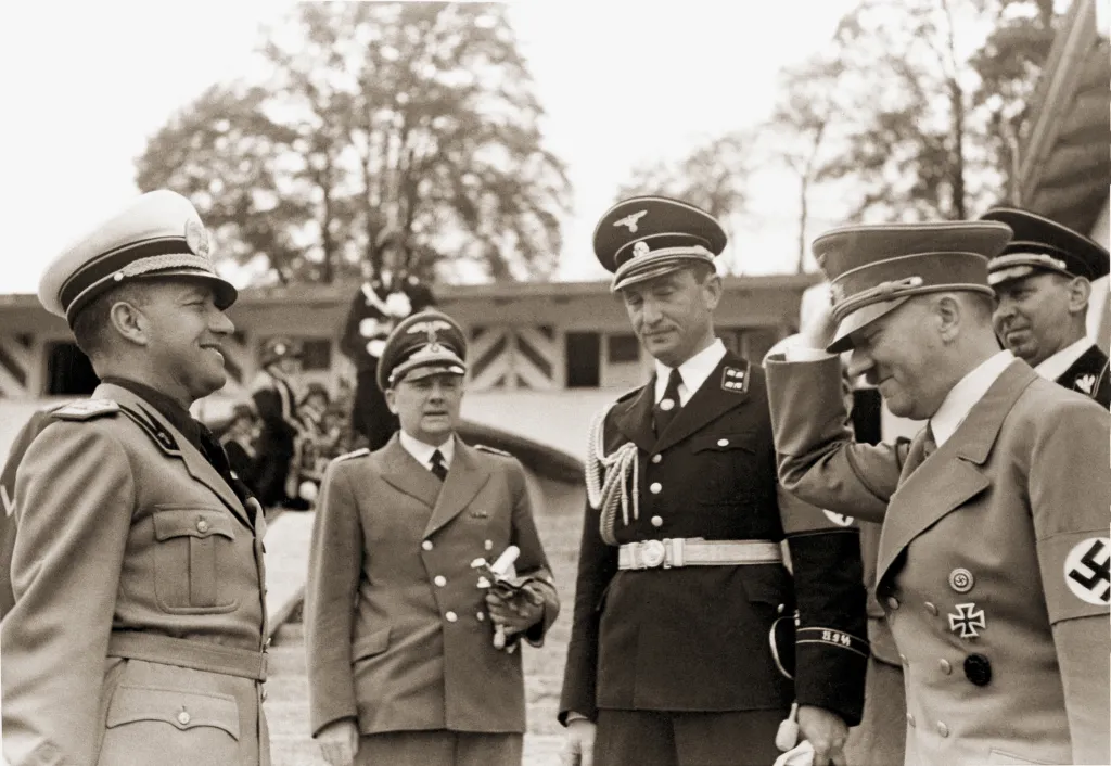Black and white photo of Italian Foreign Minister Count Galeazzo Ciano, German Nazi dictator Adolf Hitler, and interpreter Paul Schmidt meeting in Germany.