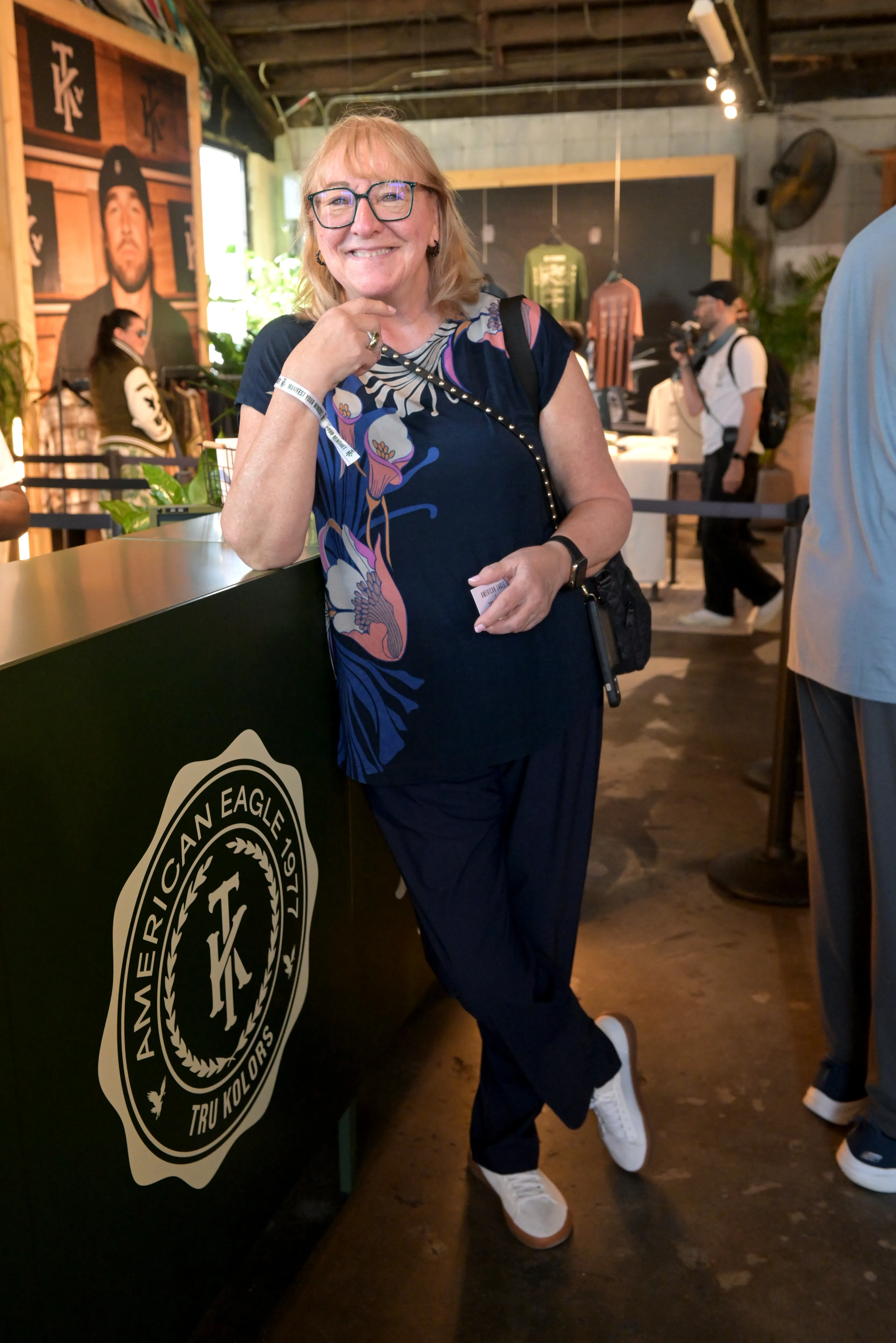 Donna Kelce leaning against a branded counter at the American Eagle pop-up event.
