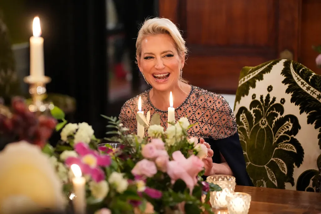 Dorinda Medley smiles at a candlelit dinner table decorated with floral arrangements.