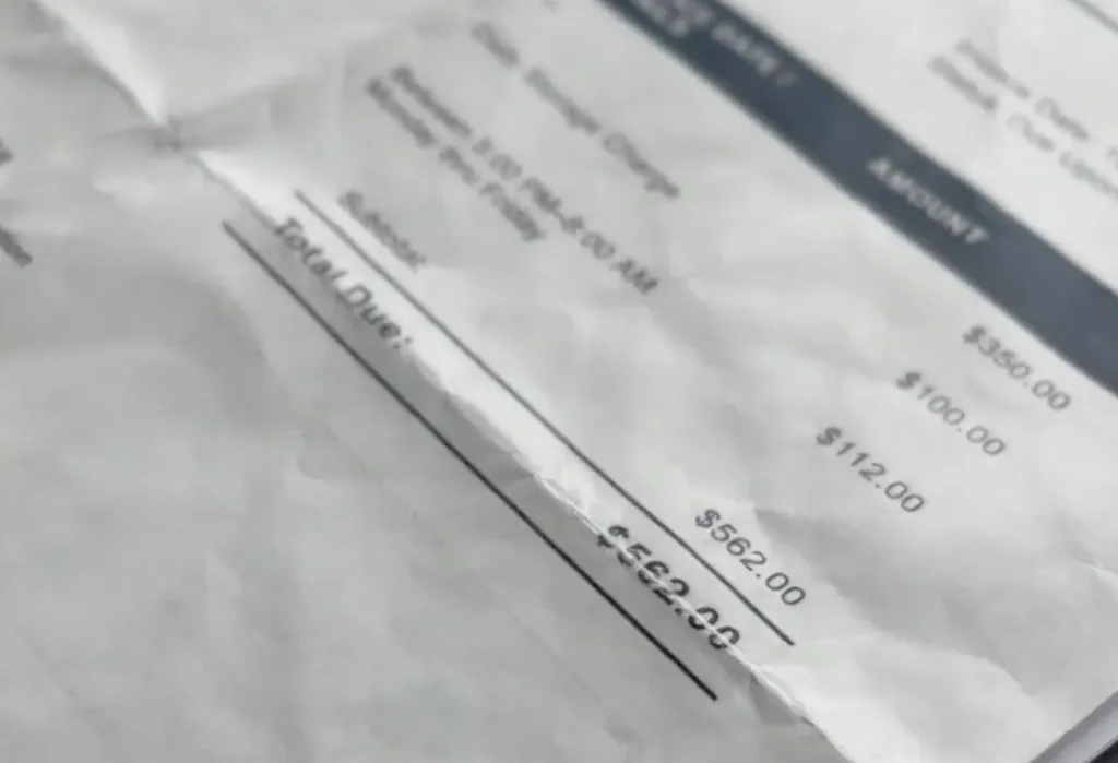 A crumpled towing fee invoice showing a total due of $562.00.