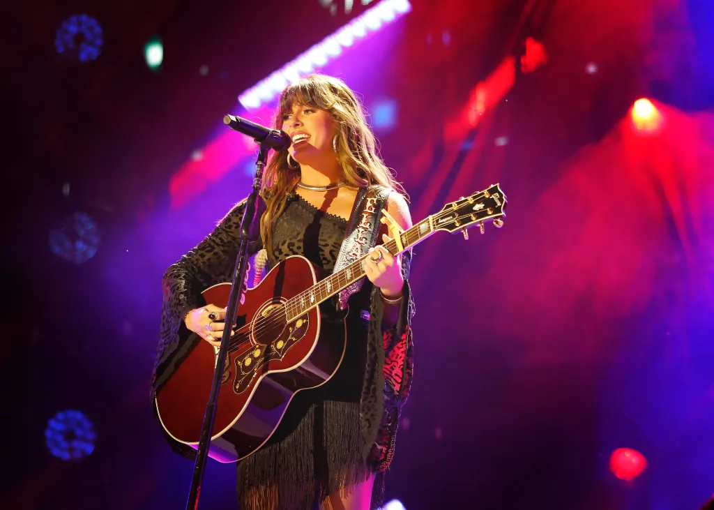 Ella Langley performs on stage while playing an acoustic guitar.