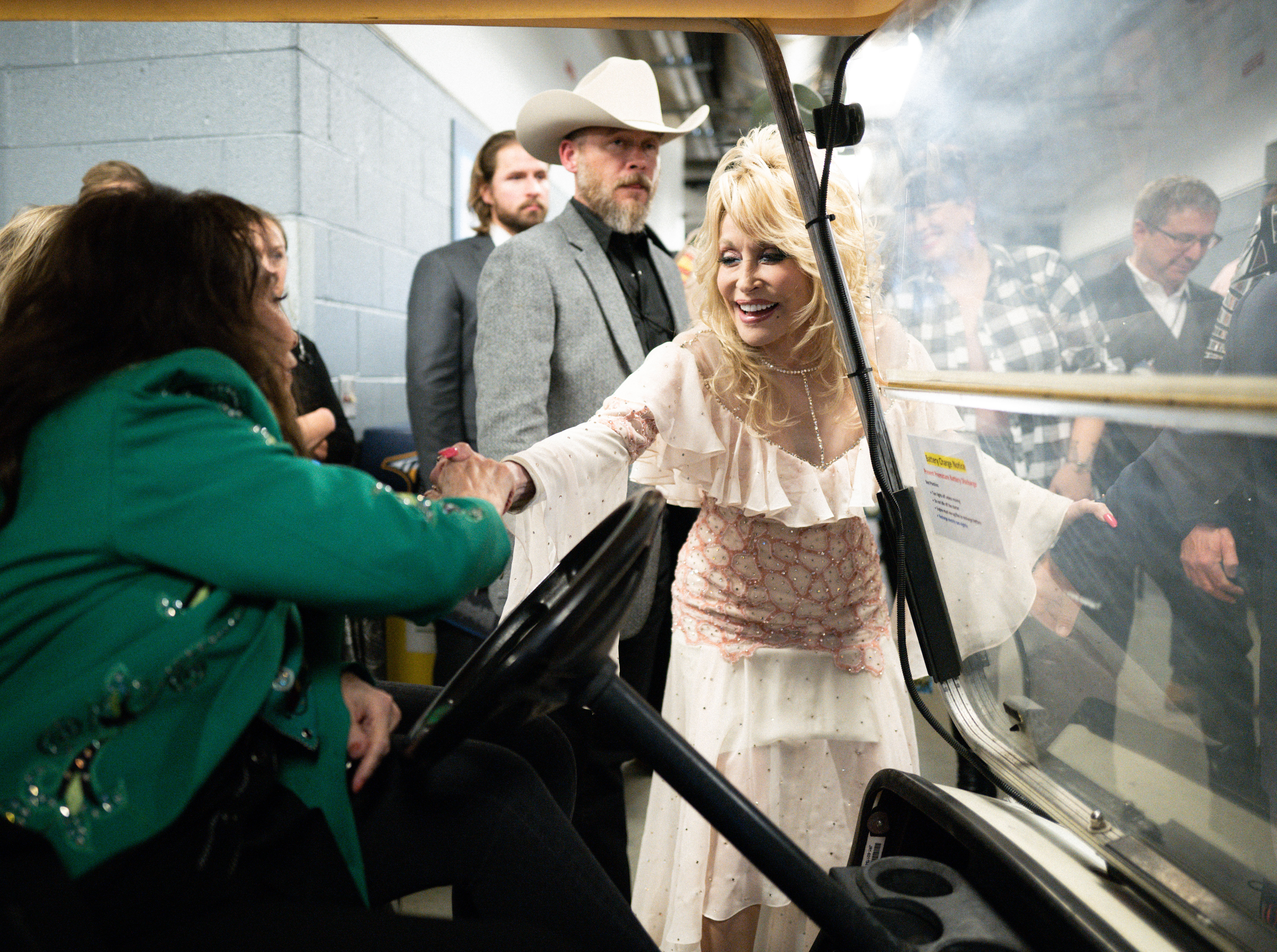 Loretta Lynn and Dolly Parton shaking hands backstage.