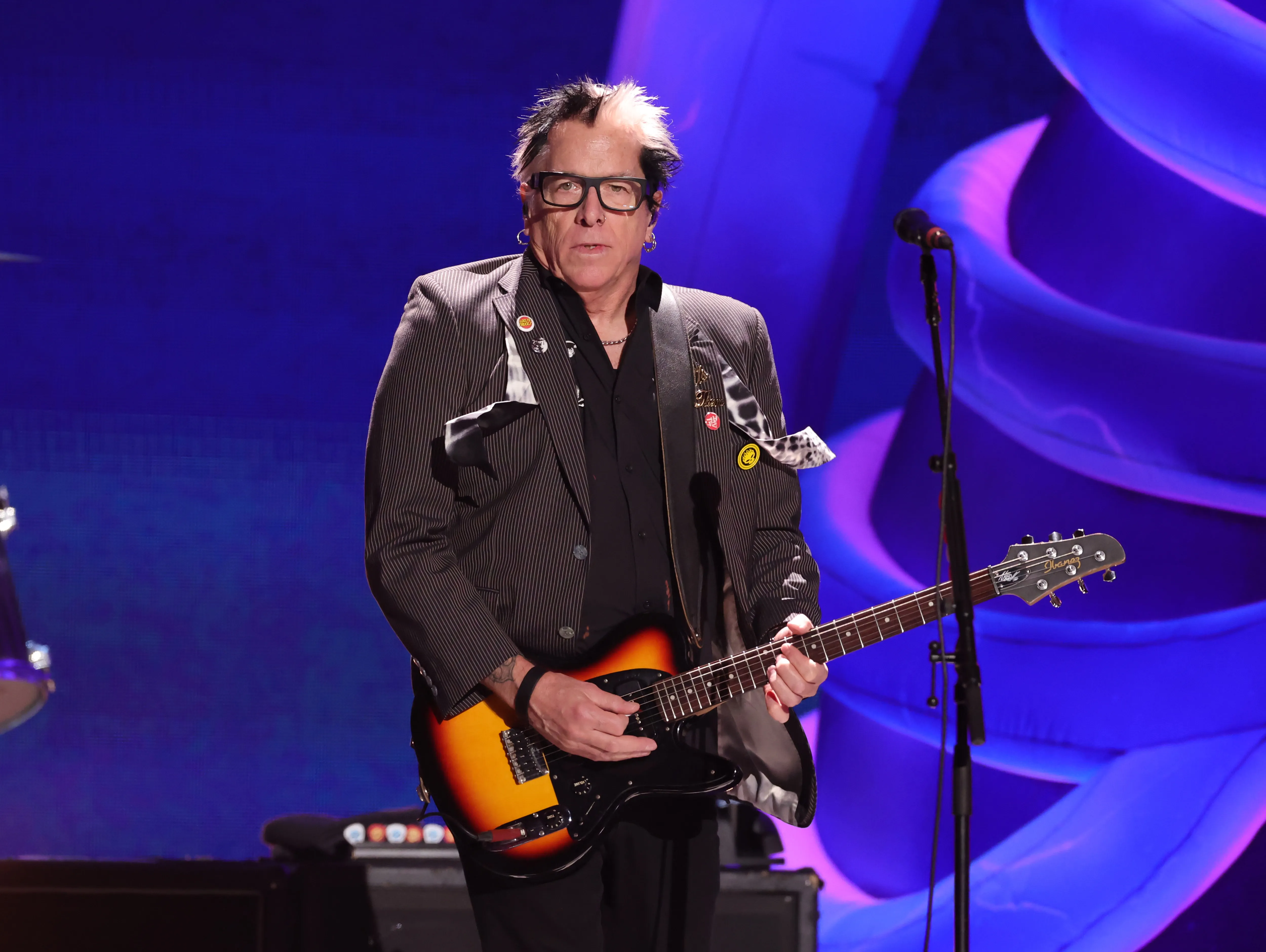 Noodles of The Offspring performs onstage playing an electric guitar.