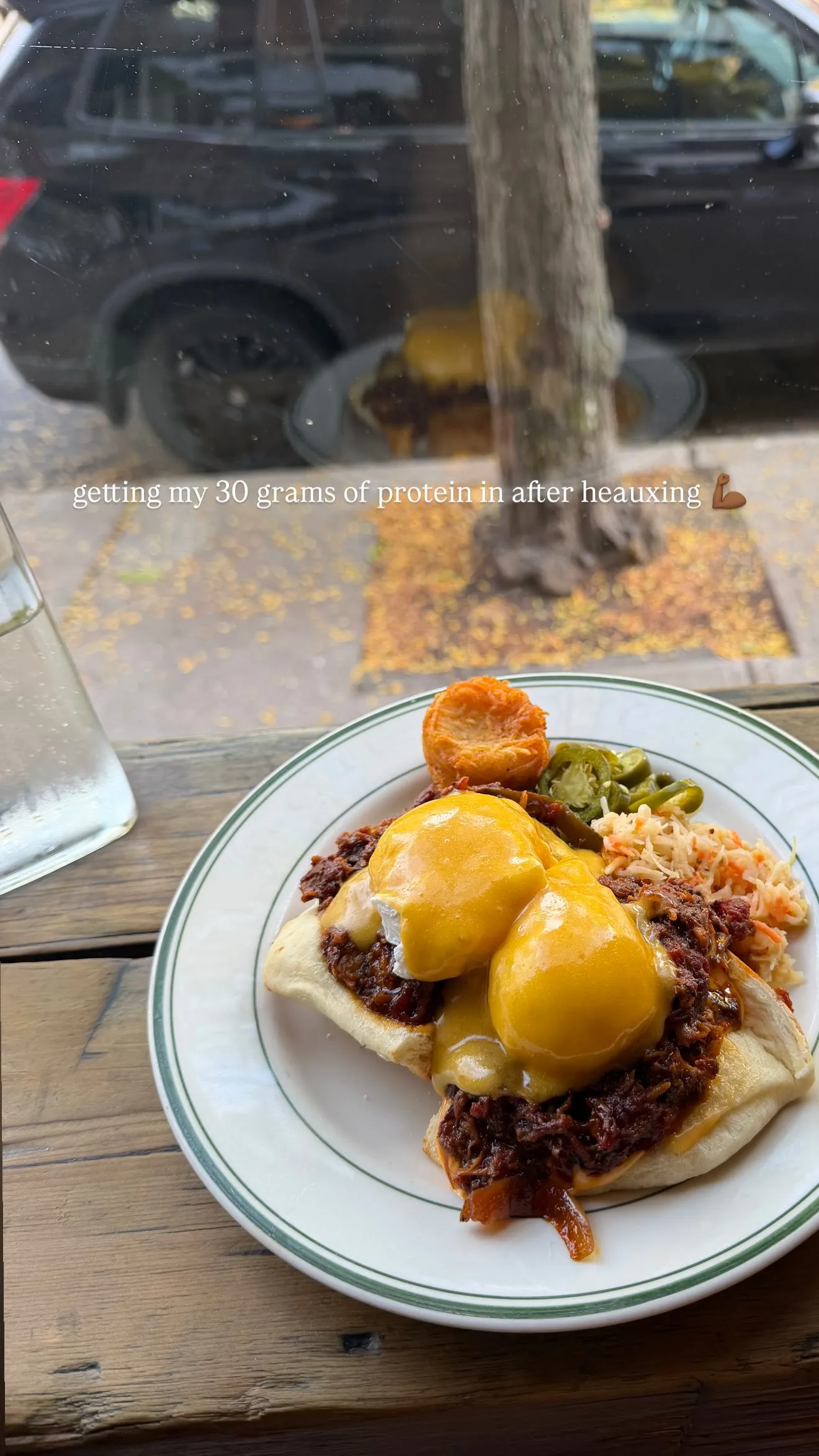 A plate of eggs Benedict with pulled pork, pickled jalapenos, and a side of shredded cabbage.