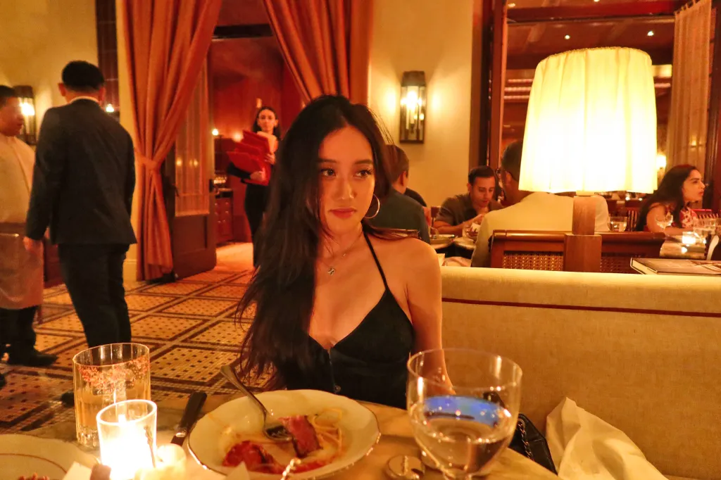 Elsa Cai seated at a restaurant table with half-eaten food.