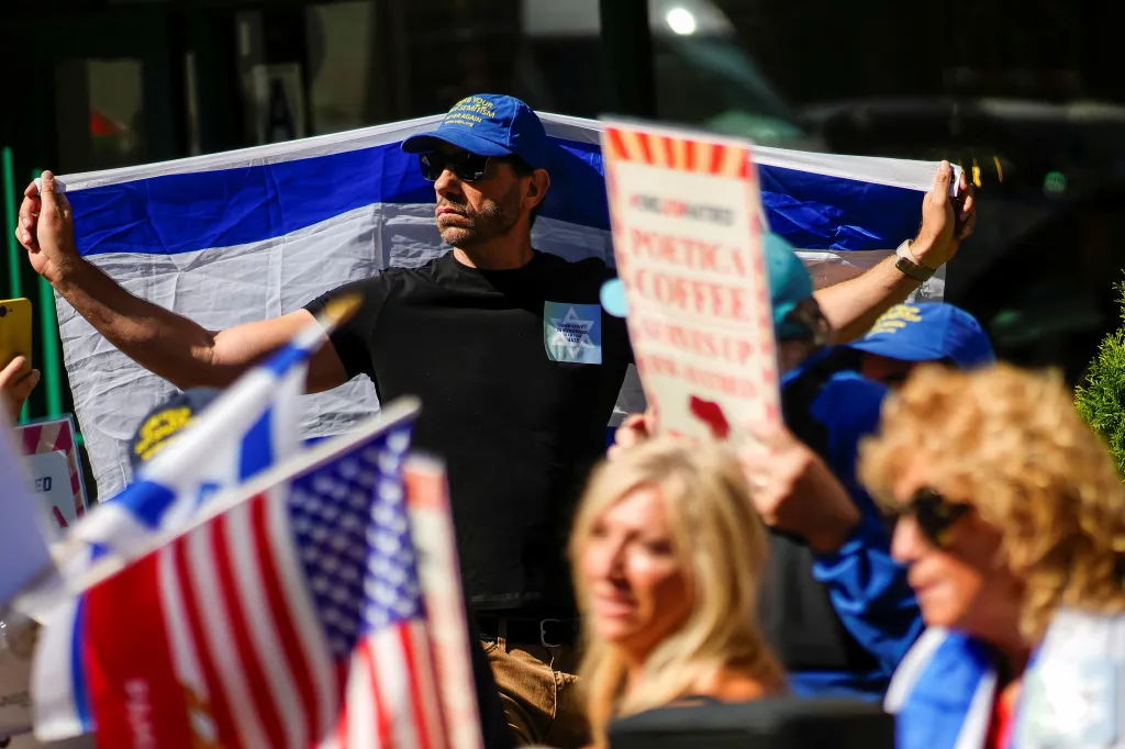 A demonstrator holds an Israeli flag during an '#EndJewHatred' rally outside Poetica Coffee in New York.