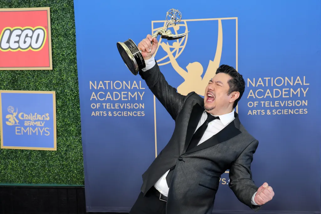 Eric Bauza joyfully raises an Emmy award in the press room at the Children's and Family Emmy Awards.