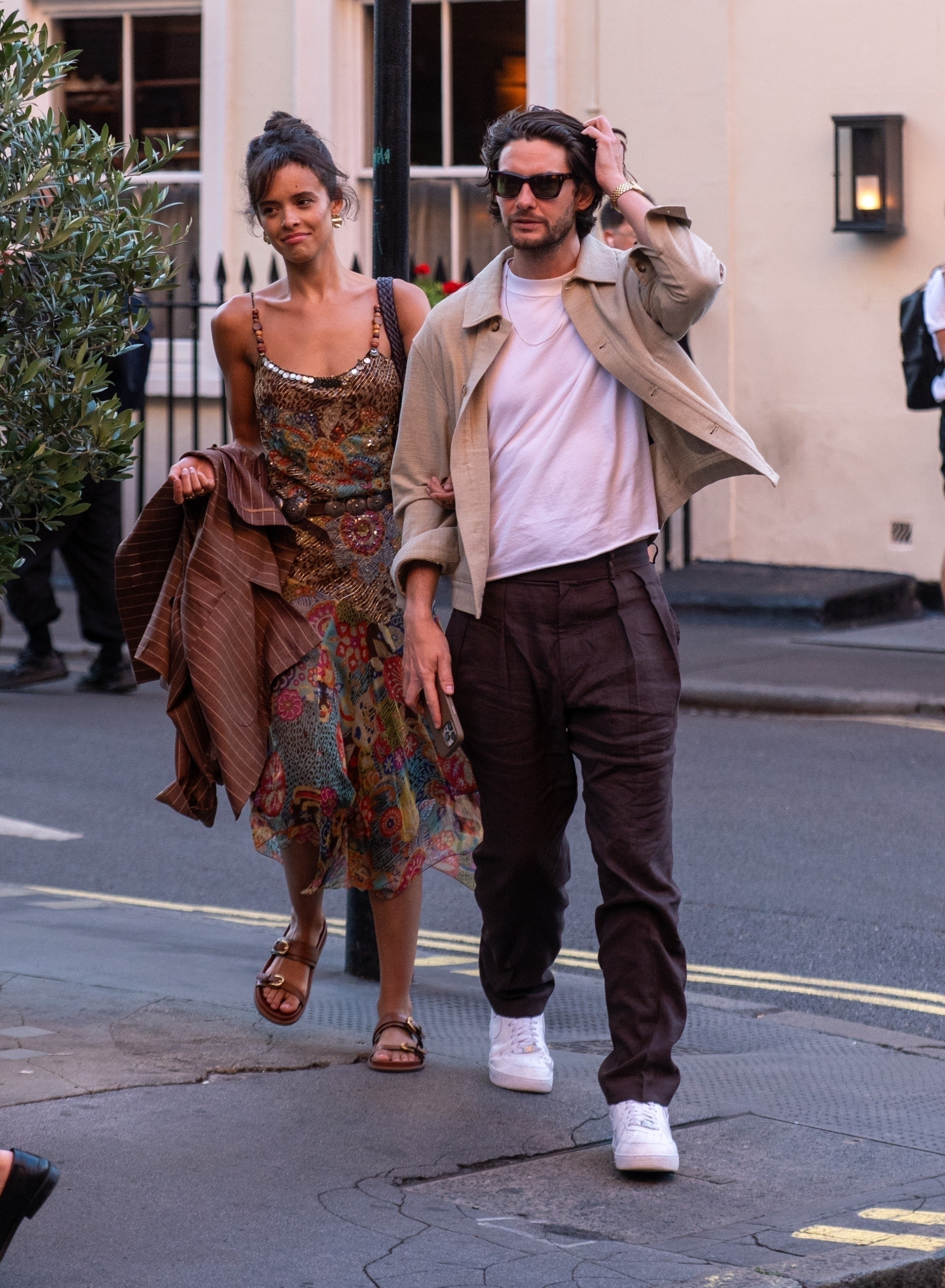 Ben Barnes and Aubrey Cleland walk arm in arm down a London street.