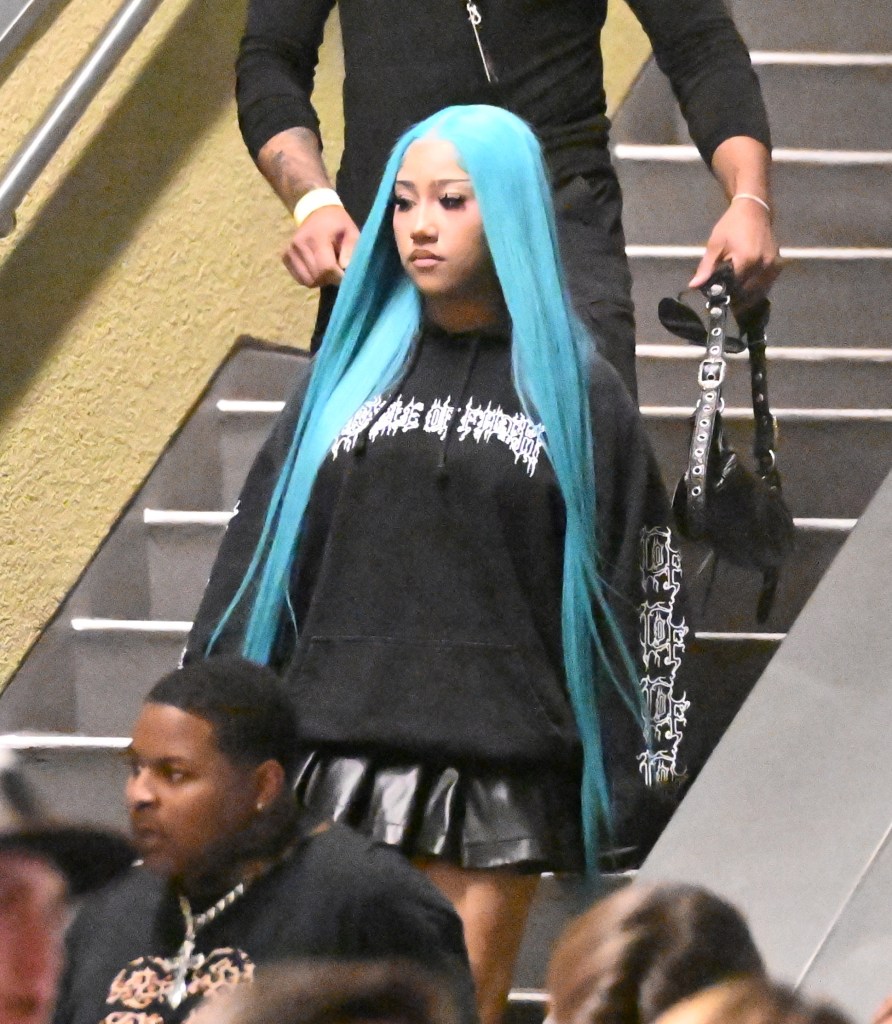 North West with bright blue hair walks down stairs at Universal Studios Hollywood, accompanied by bodyguards.