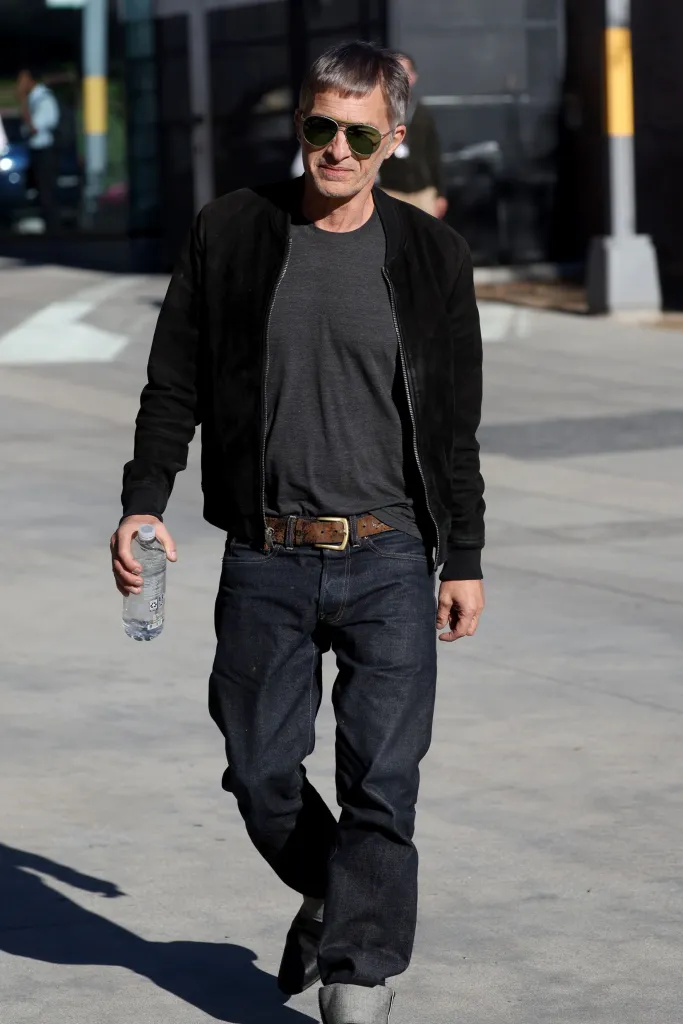 Actor Olivier Martinez walking outside while holding a water bottle.