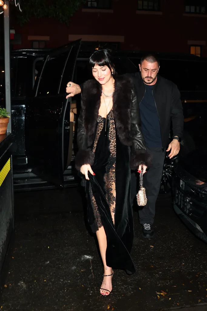 Dakota Johnson arrives at a restaurant in a black Stella McCartney dress, fur-trimmed leather coat, and strappy heels.