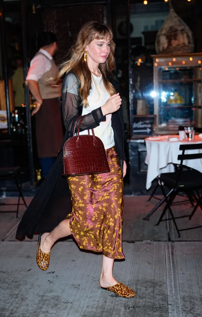 Jennifer Lawrence arrives at a restaurant in New York City, wearing a patterned skirt and holding a maroon handbag.