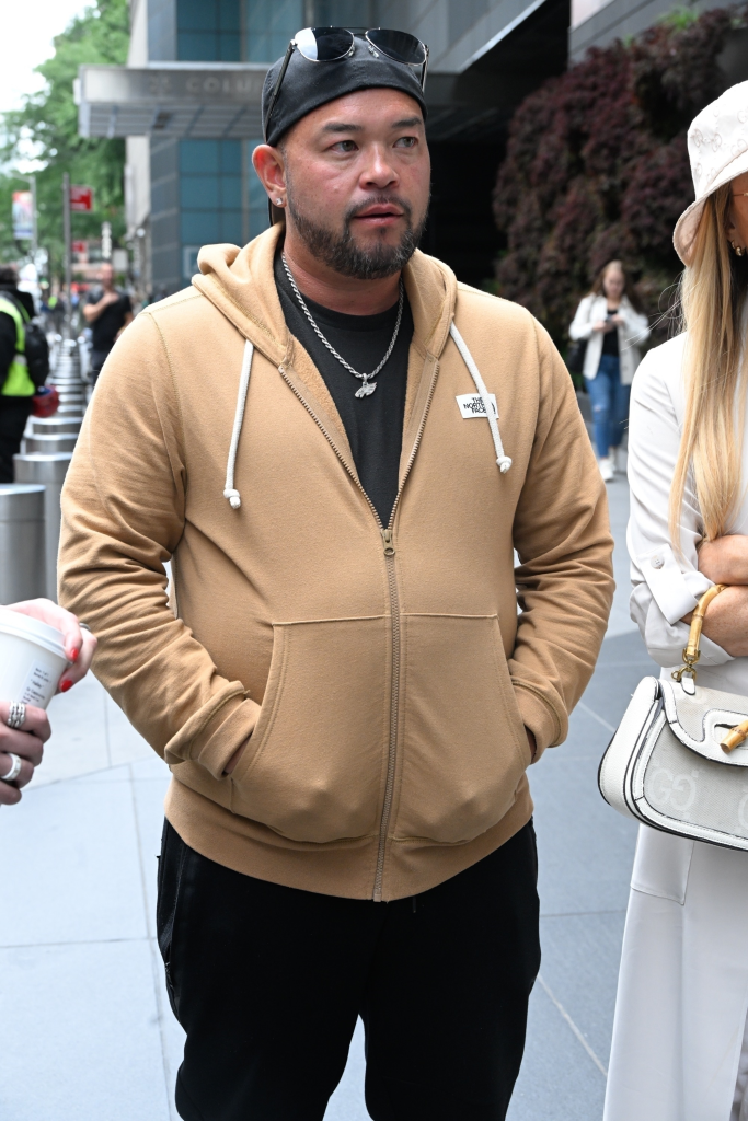 Jon Gosselin wearing a tan hoodie, black t-shirt, and a baseball cap outdoors in New York City.