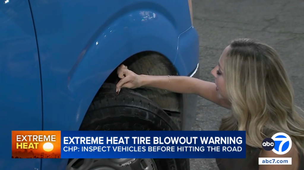 A woman using a coin to check the tread depth of a car tire.