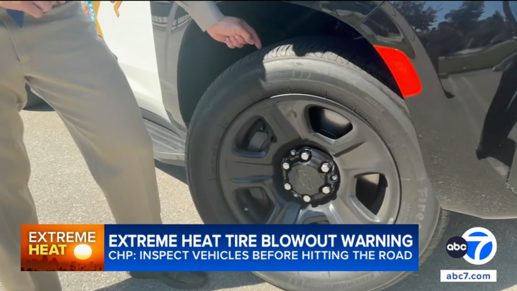 A law enforcement officer inspecting a vehicle's tire tread.