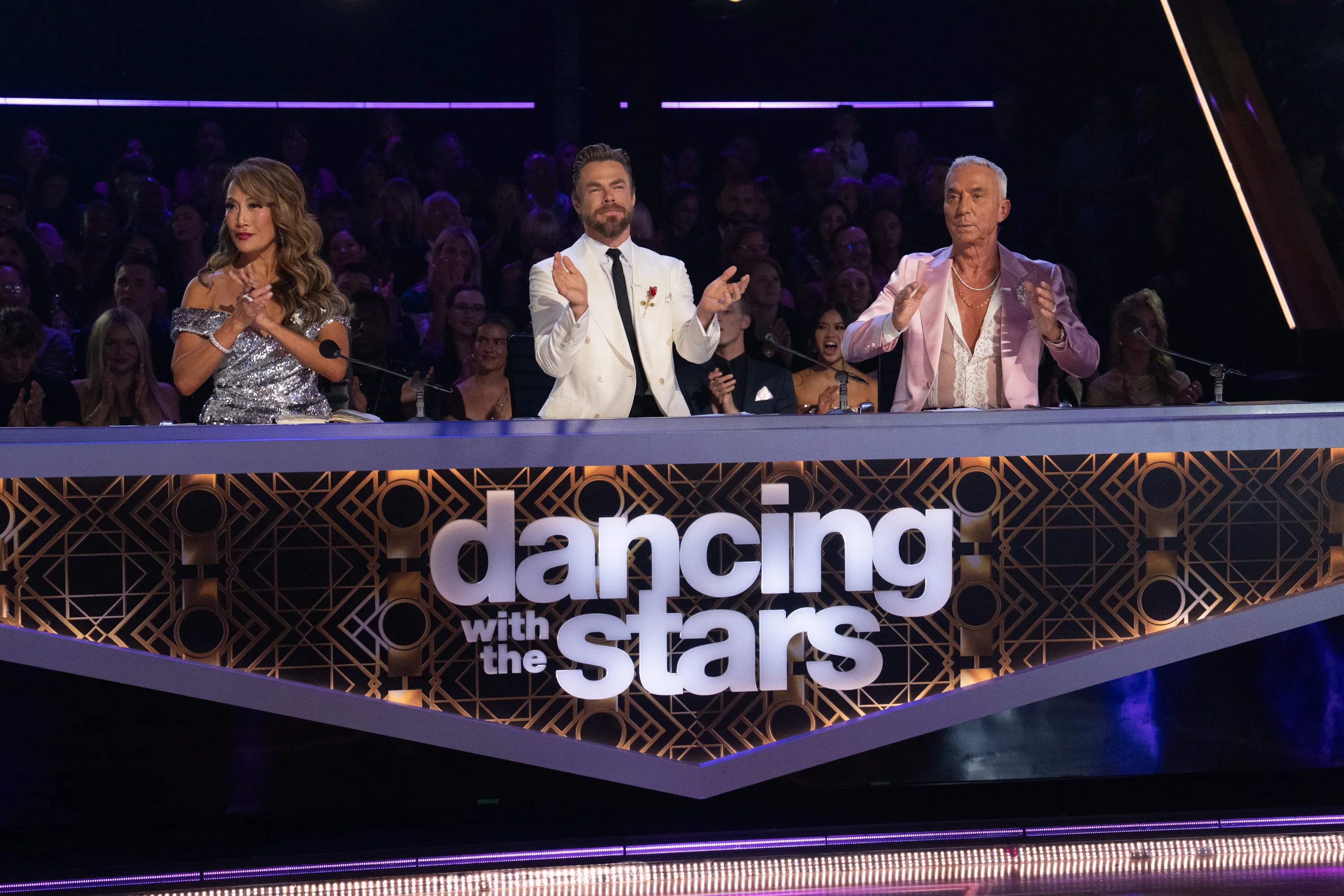 Carrie Ann Inaba, Derek Hough, and Bruno Tonioli seated at the Dancing with the Stars judges' table.