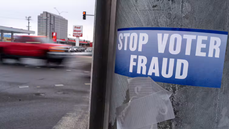 A bumper sticker in a post reads 'Stop Voter Fraud.'