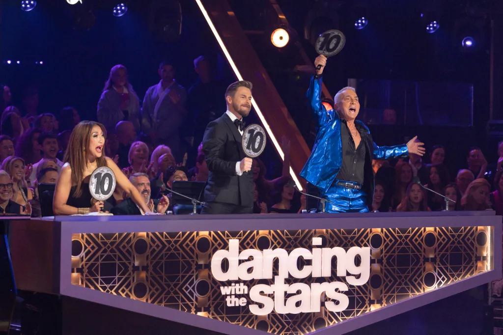 Carrie Ann Inaba, Derek Hough, and Bruno Tonioli holding up 10 paddles at the judges' table on Dancing with the Stars.