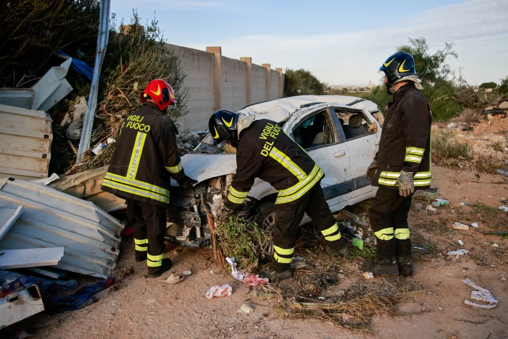 Firefighters examine a damaged car among debris after a tornado struck Petrosino, Sicily, Italy.