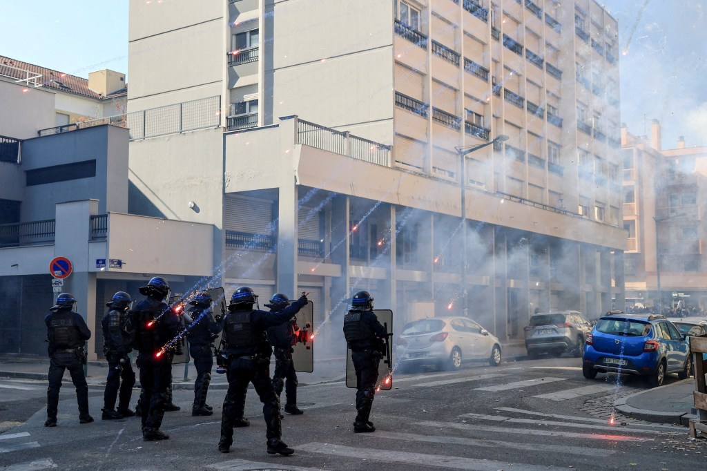 Fireworks explode near French riot police officers during a demonstration in Lyon, France.