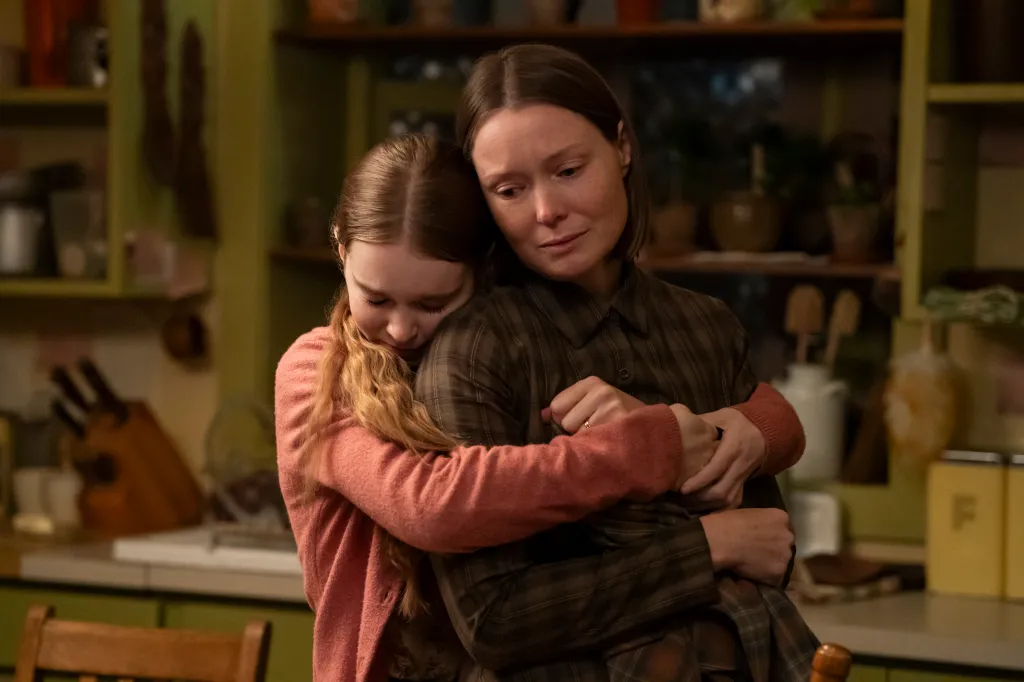 Summer H. Howell and Samantha Sloyan embrace tightly in a kitchen setting in 