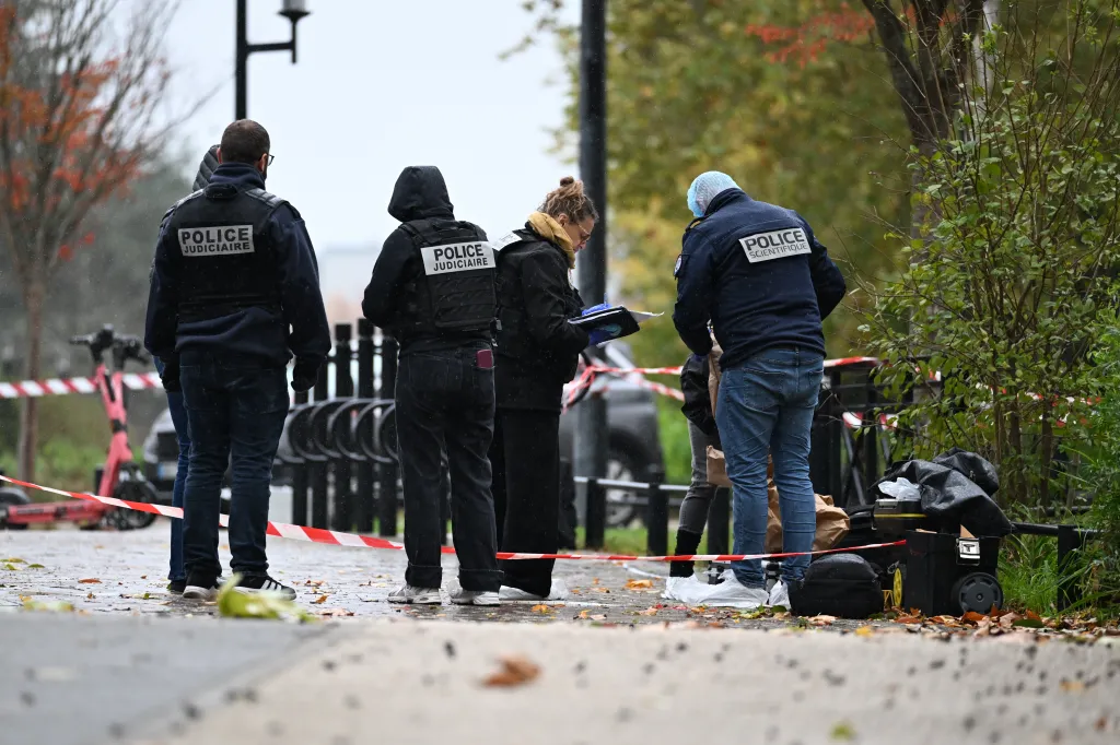 Forensic investigators and police search for evidence at a crime scene behind police tape.