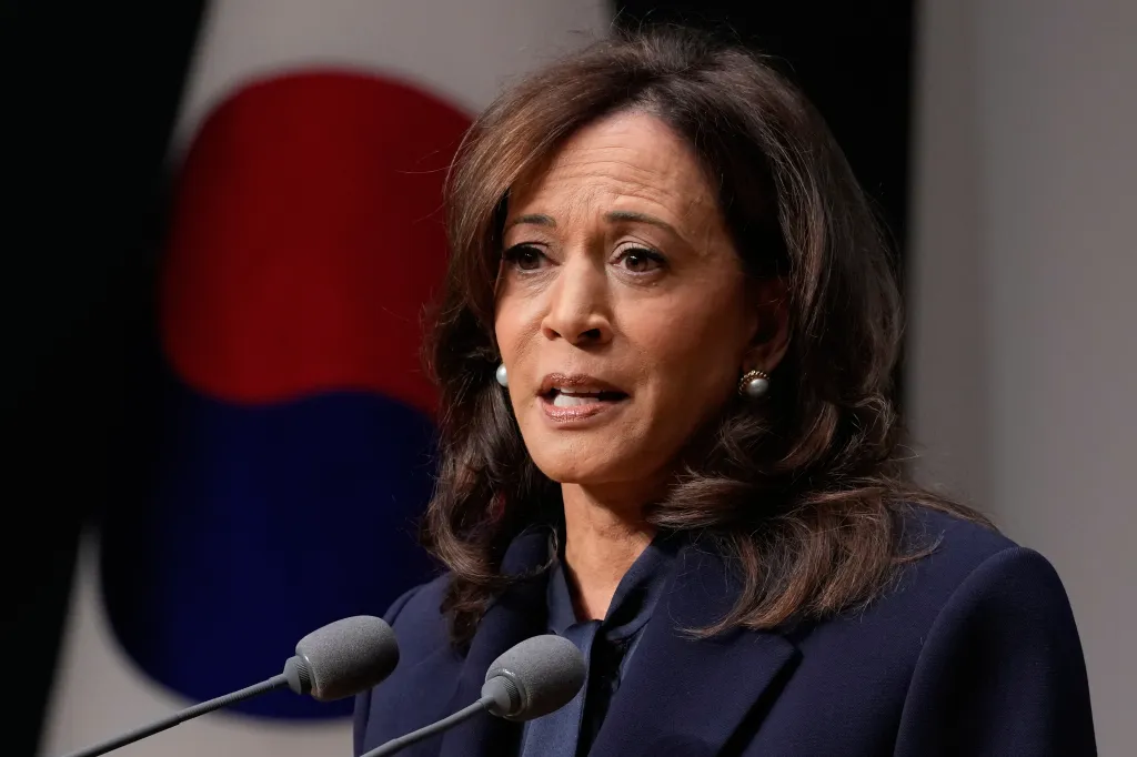 Former U.S. Vice President Kamala Harris speaks at a podium with microphones in front of a South Korean flag.