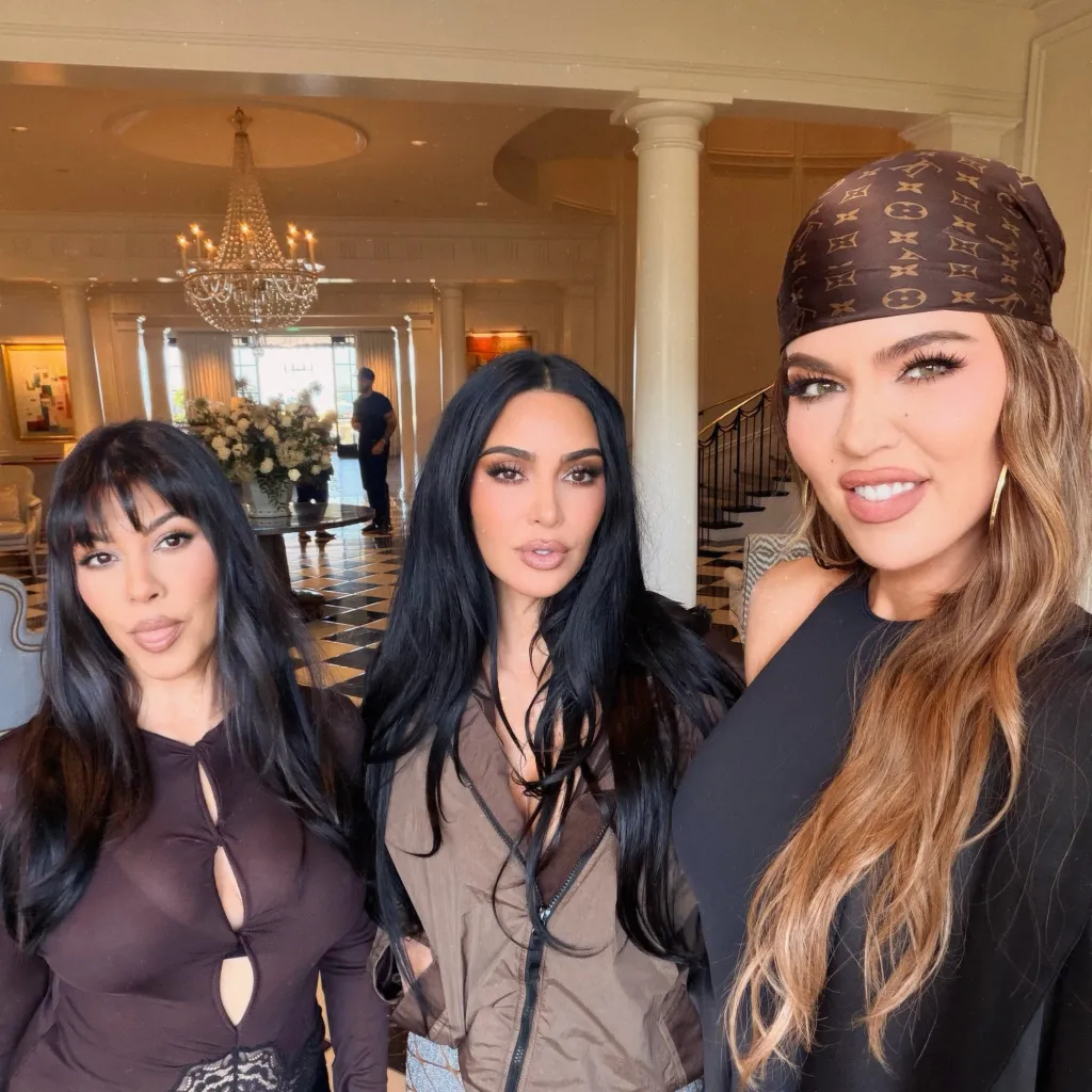 Kourtney, Kim, and Khloe Kardashian posing together indoors.