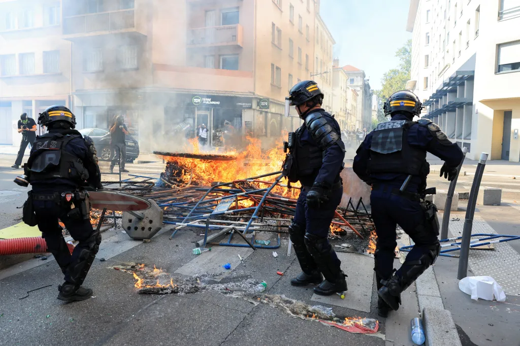 French CRS riot police officers clear a burning street barricade during student protests in Lyon.