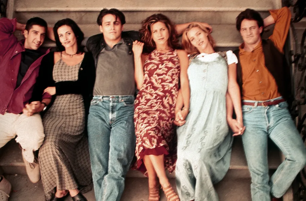Cast photo of the television show Friends, featuring David Schwimmer, Courteney Cox, Matt LeBlanc, Jennifer Aniston, Lisa Kudrow, and Matthew Perry lying side by side on steps.