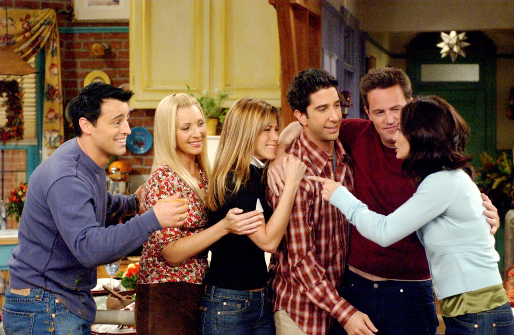 The main cast of the television show Friends—Matt LeBlanc, Lisa Kudrow, Jennifer Aniston, David Schwimmer, Matthew Perry, and Courteney Cox—standing together in an apartment.