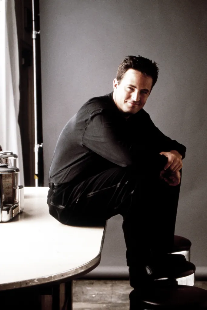 Portrait of Matthew Perry sitting on a counter.