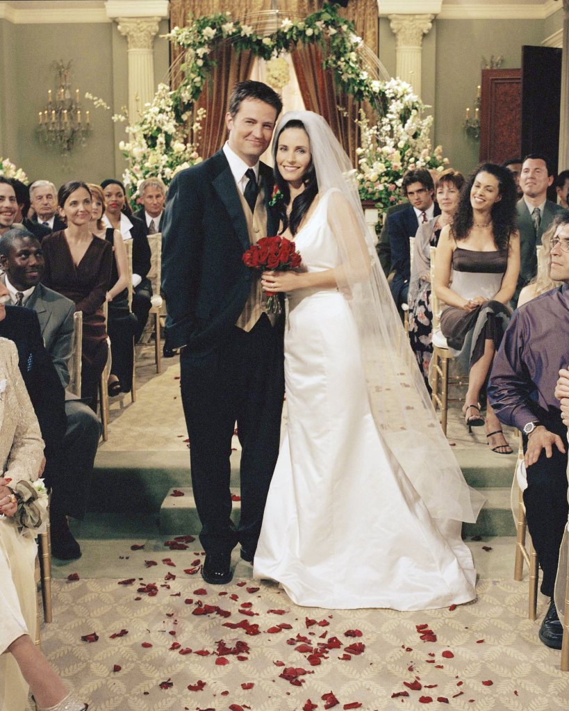 Chandler Bing and Monica Geller on their wedding day, standing together in front of guests.