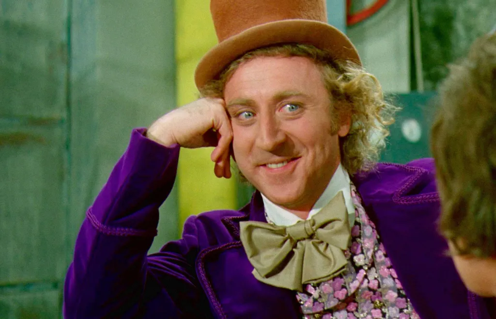 Gene Wilder as Willy Wonka smiling while resting his chin in his hand.