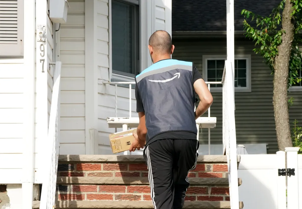 An Amazon deliveryman drops off a package on a porch.