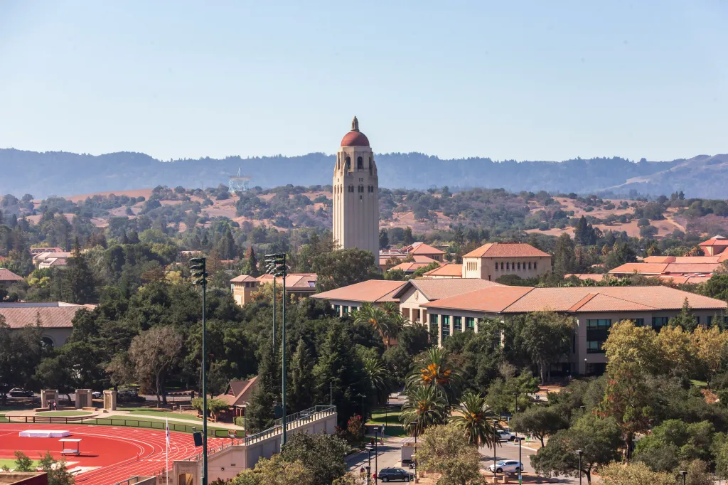 A general view of the Stanford University campus, including Hoover Tower, with foothills in the background and a running track in the foreground.